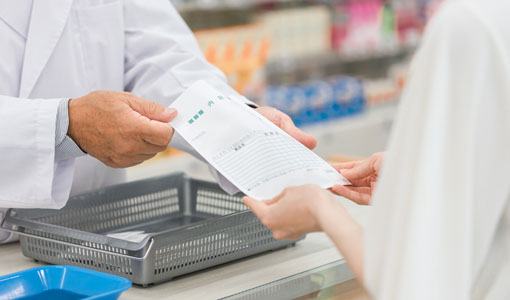 pharmacist handing prescription to customer